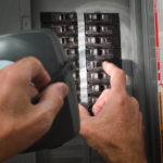 man with flashlight at residential circuit breaker panel