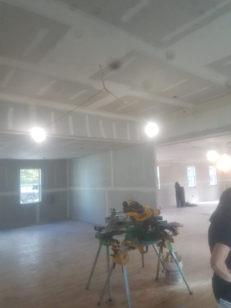 ANGLED VIEW OF UNFINISHED HOME SHOWING ELECTRICAL WORK BEING DONE BY ELECTRICIAN